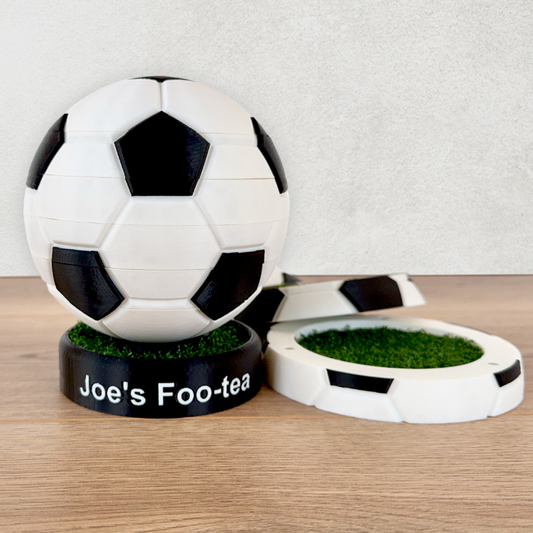 A picture of 4 coasters in a football shape with artificial grass inserts on a wooden worktop